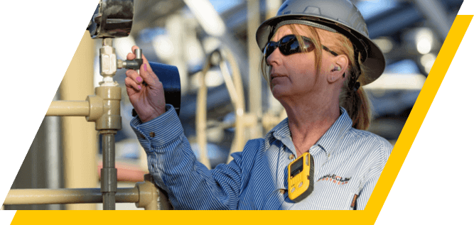 Kinetik employee wearing gas detection safety monitor while reading a meter