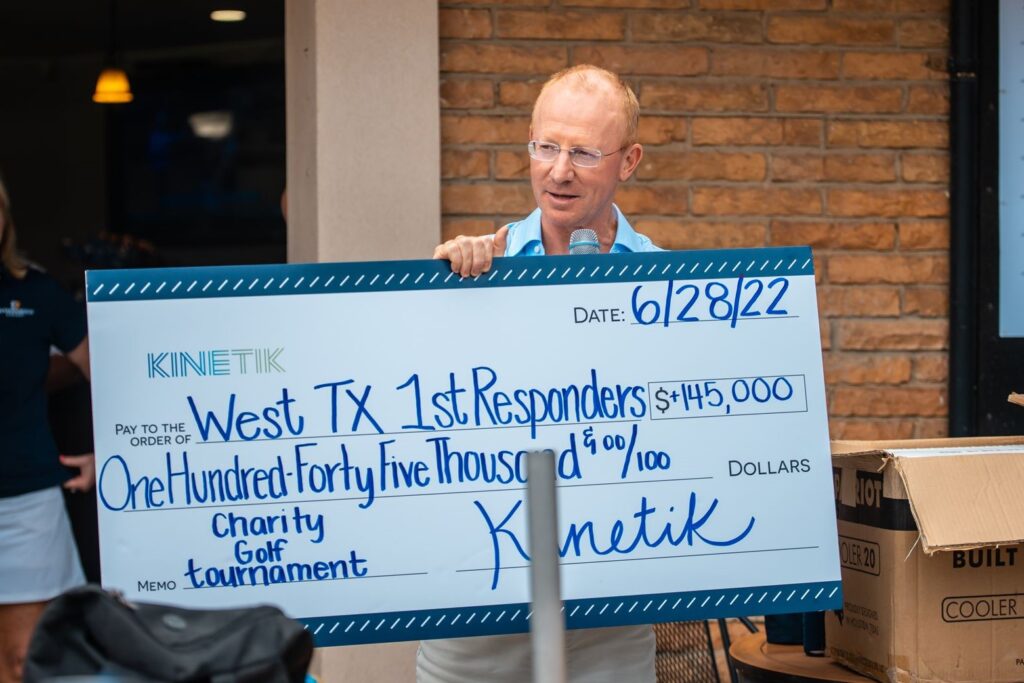Picture of Kinetik CEO, Jamie Welch with a check for charity